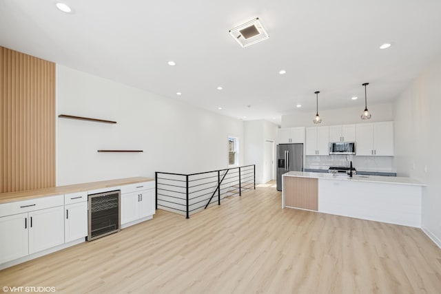 kitchen featuring wine cooler, open shelves, stainless steel appliances, light wood-style floors, and white cabinets