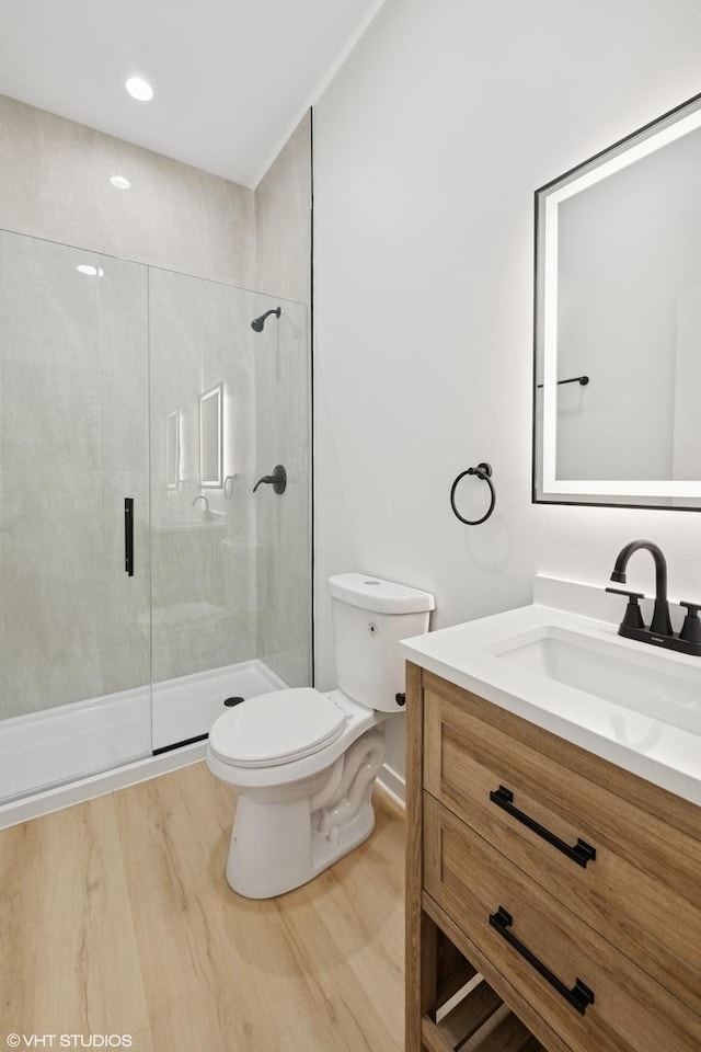 full bath with vanity, wood finished floors, a shower stall, and toilet