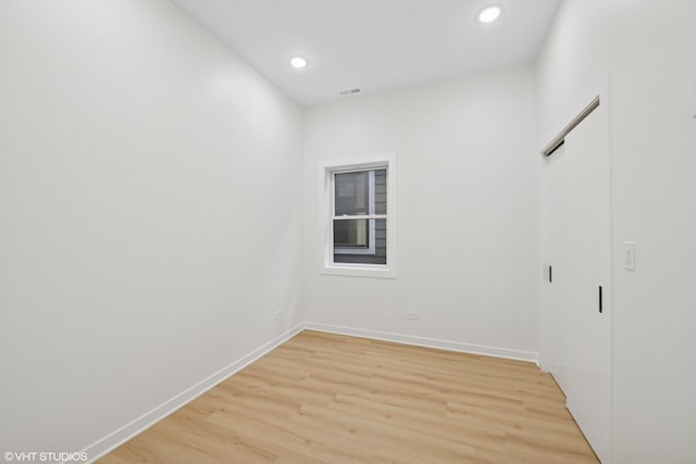 empty room with light wood-style flooring, visible vents, baseboards, and recessed lighting