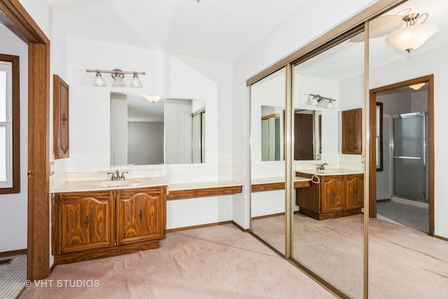 bathroom with vanity, a shower with shower door, and decorative backsplash