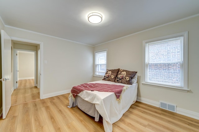 bedroom with crown molding and light hardwood / wood-style floors