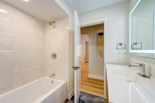 bathroom with tiled shower / bath combo, wood-type flooring, and vanity