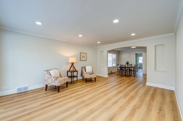 living area with ornamental molding and light hardwood / wood-style flooring