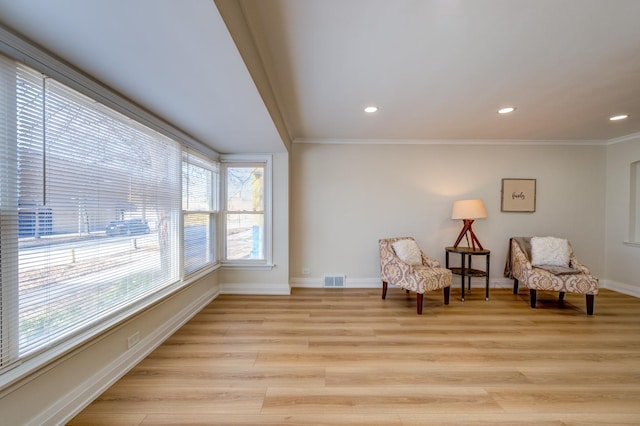 living area with ornamental molding and light hardwood / wood-style flooring