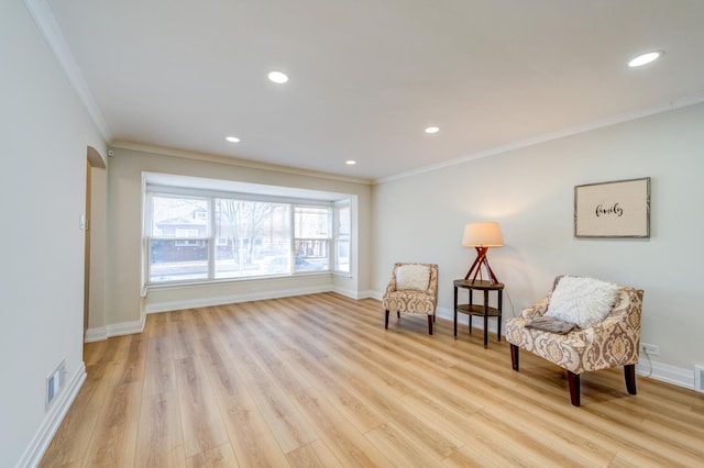 living area featuring ornamental molding and light hardwood / wood-style flooring