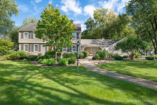 colonial-style house featuring a front yard and a chimney