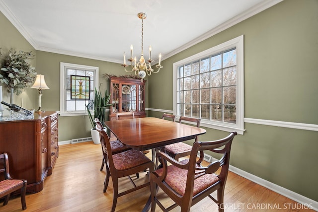 dining area featuring an inviting chandelier, light wood-style flooring, visible vents, and ornamental molding