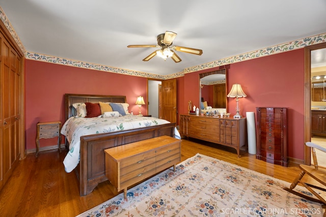 bedroom with ensuite bath, wood finished floors, baseboards, and ceiling fan