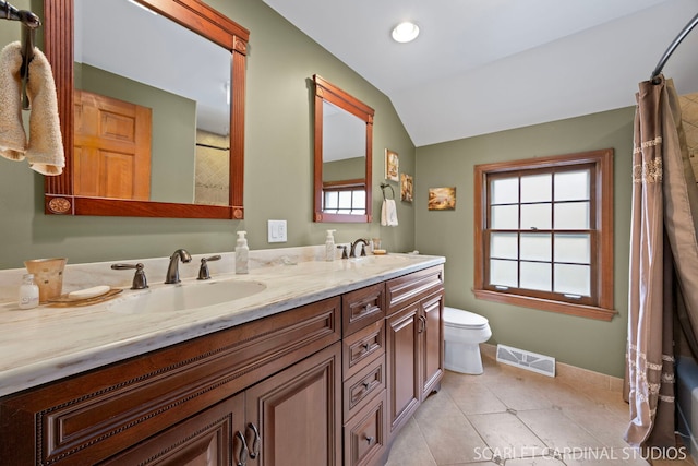 bathroom with visible vents, toilet, lofted ceiling, and a sink