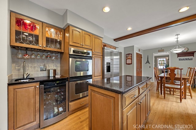 kitchen featuring light wood-style flooring, a sink, stainless steel appliances, wine cooler, and brown cabinetry