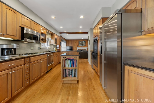 kitchen with light wood-type flooring, a sink, tasteful backsplash, a center island, and stainless steel appliances