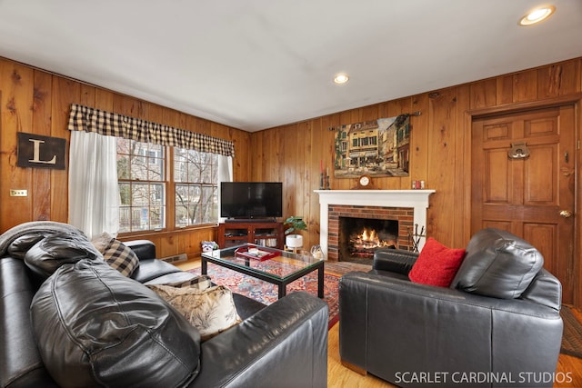 living area with recessed lighting, a brick fireplace, and wood walls