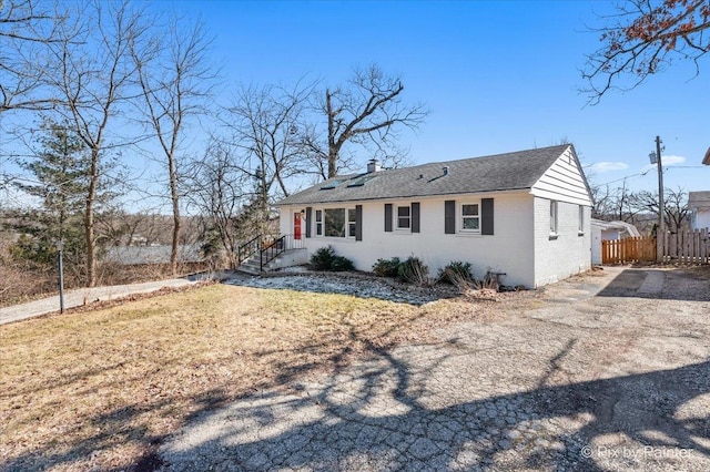 view of front of property with brick siding, fence, and a chimney