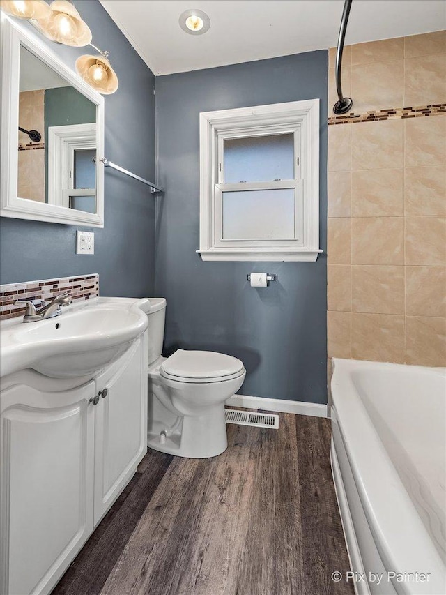 bathroom with toilet, wood finished floors, vanity, visible vents, and baseboards