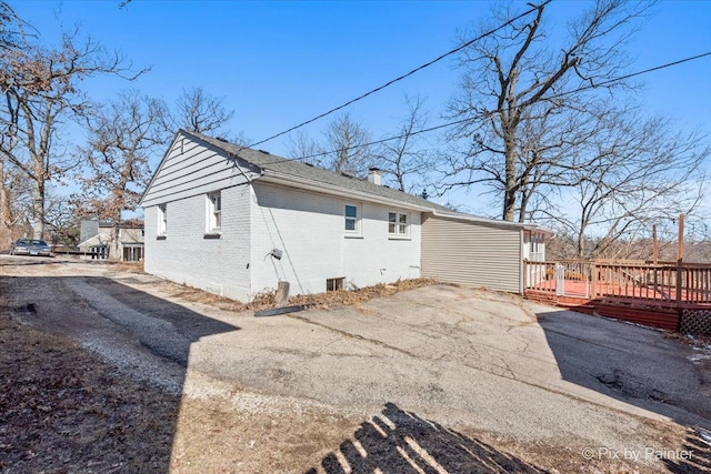 view of home's exterior with a chimney, a deck, and brick siding