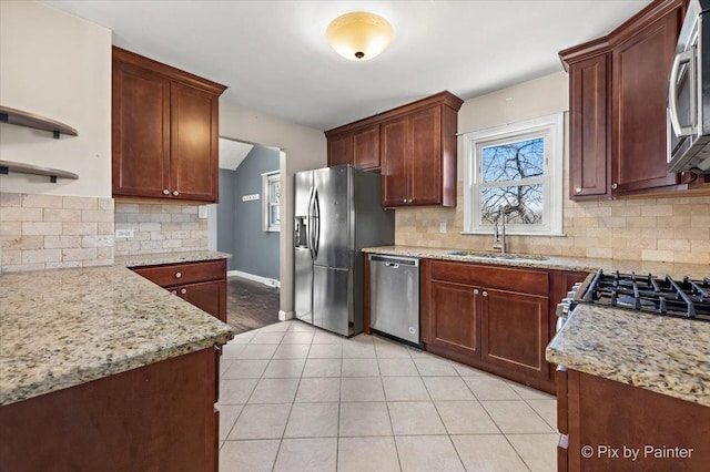 kitchen with light tile patterned floors, stainless steel appliances, a sink, light stone countertops, and tasteful backsplash