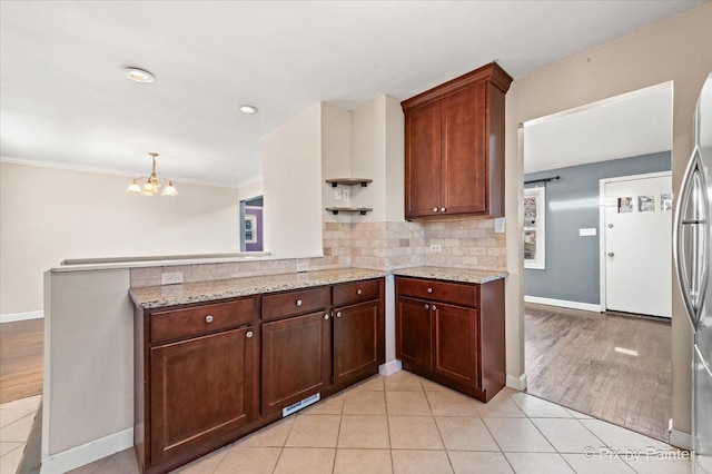 kitchen featuring light tile patterned floors, light stone counters, a peninsula, backsplash, and open shelves