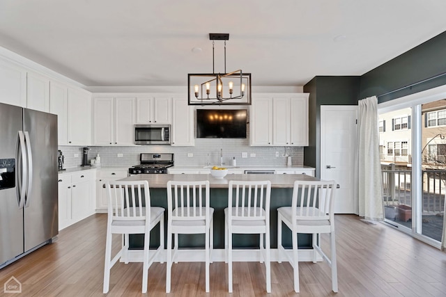 kitchen featuring white cabinetry, decorative light fixtures, stainless steel appliances, and a kitchen island