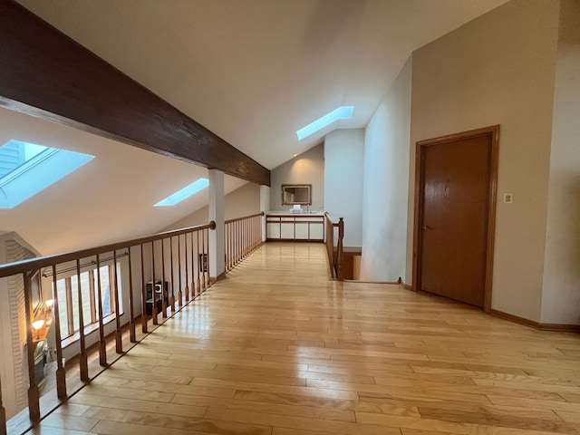 additional living space with high vaulted ceiling, beam ceiling, a skylight, and light hardwood / wood-style floors