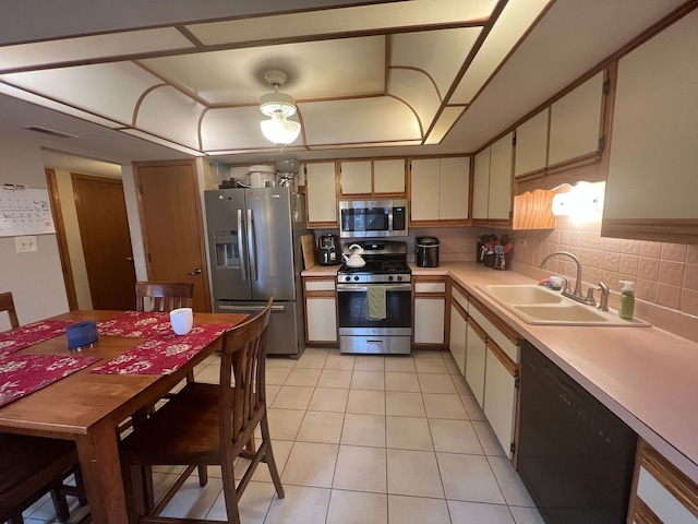 kitchen featuring sink, light tile patterned floors, stainless steel appliances, tasteful backsplash, and cream cabinets