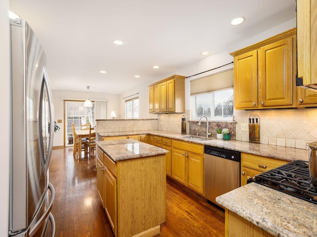 kitchen with sink, decorative light fixtures, a center island, appliances with stainless steel finishes, and light stone countertops