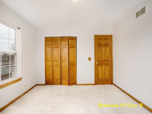 unfurnished bedroom featuring light colored carpet and a closet