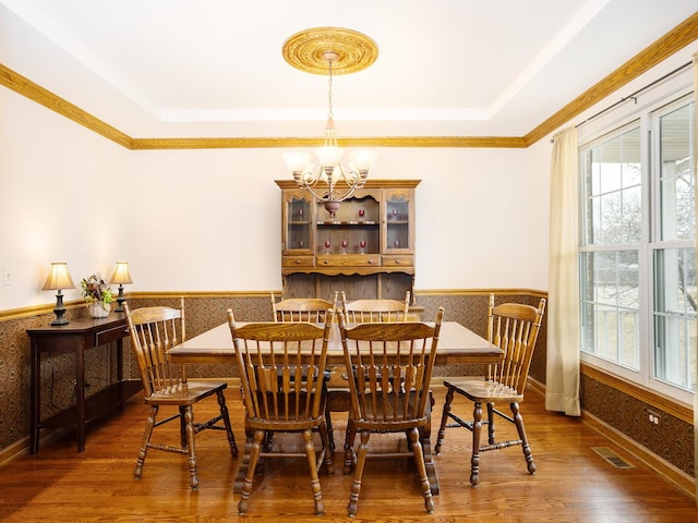 dining room featuring dark hardwood / wood-style floors, ornamental molding, a tray ceiling, and a notable chandelier