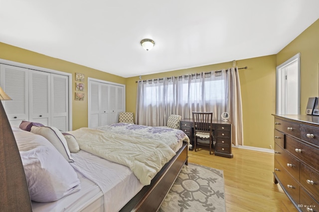 bedroom with two closets and light hardwood / wood-style flooring