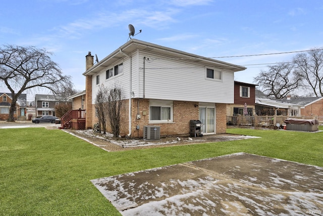 rear view of house with central AC and a lawn