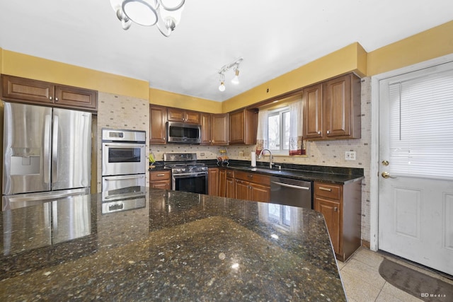 kitchen with backsplash, sink, dark stone counters, and appliances with stainless steel finishes