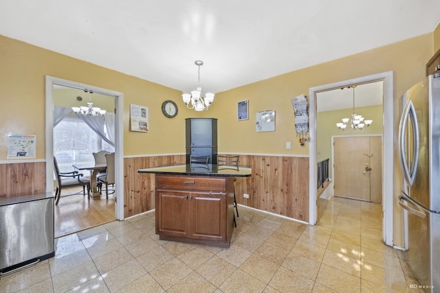 kitchen with stainless steel refrigerator, wooden walls, and a notable chandelier