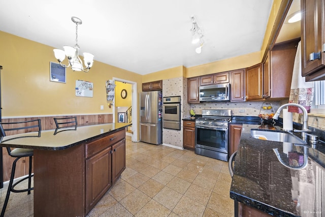 kitchen featuring appliances with stainless steel finishes, pendant lighting, sink, backsplash, and a kitchen breakfast bar