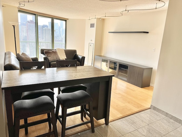 kitchen with light tile patterned floors, a breakfast bar area, a textured ceiling, and a wall of windows