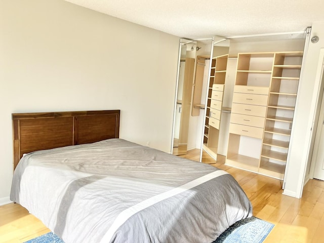 bedroom with a textured ceiling, light wood-type flooring, and a closet