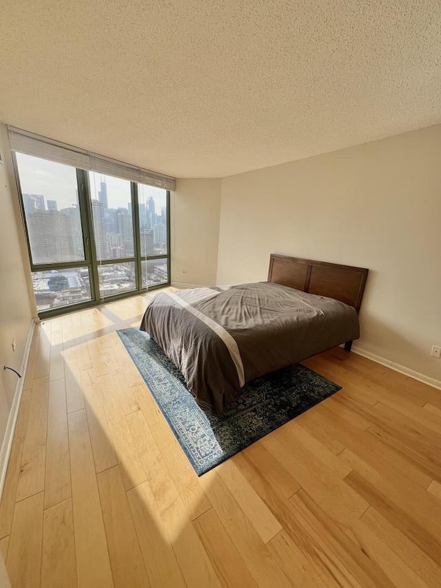 bedroom with access to outside, a textured ceiling, and light wood-type flooring