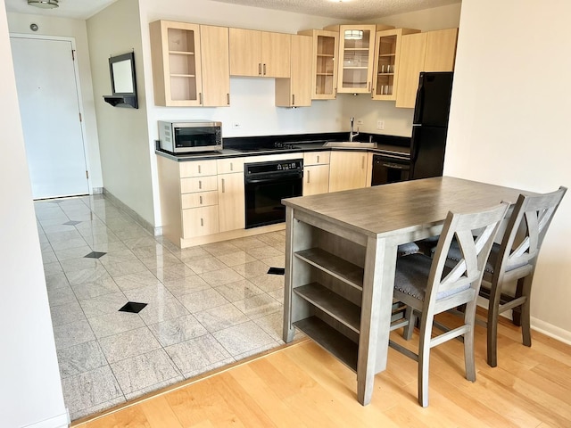 kitchen featuring light wood-type flooring, light brown cabinetry, sink, and black appliances