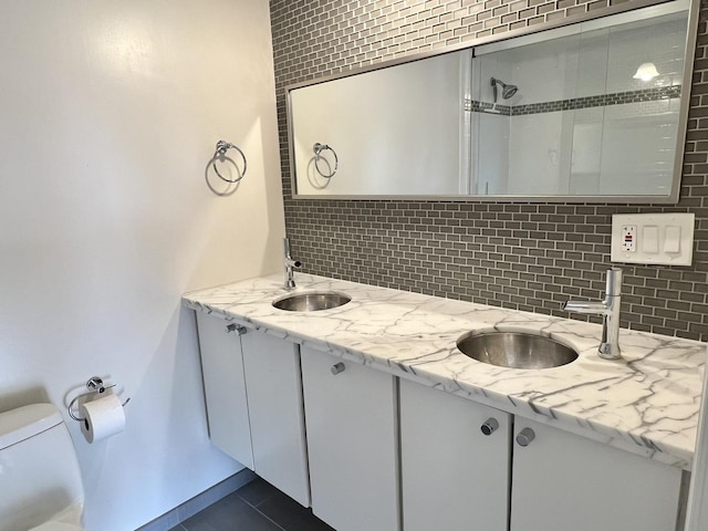 bathroom with tile patterned flooring, vanity, toilet, and decorative backsplash