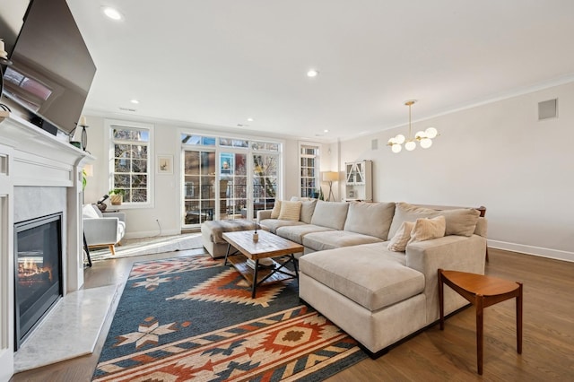 living room with hardwood / wood-style flooring, ornamental molding, a fireplace, and a chandelier