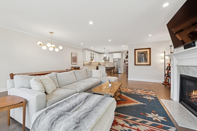 living room featuring an inviting chandelier, crown molding, a fireplace, and hardwood / wood-style flooring