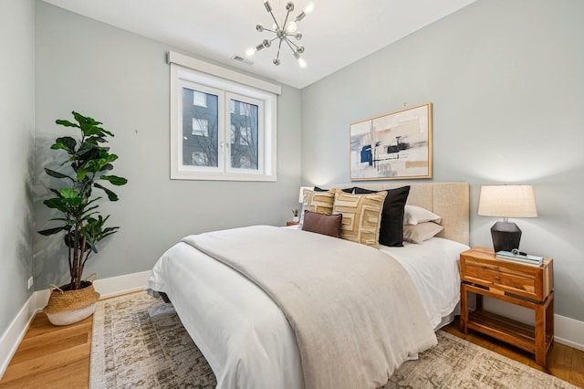 bedroom featuring wood-type flooring and a chandelier