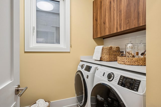 clothes washing area featuring washer and clothes dryer and cabinets