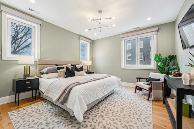 bedroom featuring an inviting chandelier and light hardwood / wood-style floors