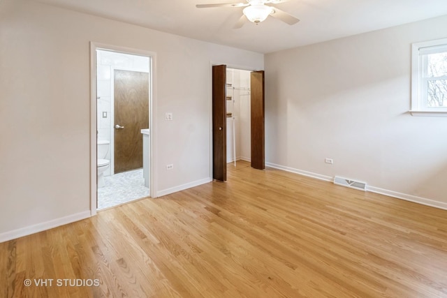 unfurnished bedroom featuring ensuite bath, ceiling fan, light hardwood / wood-style floors, a spacious closet, and a closet