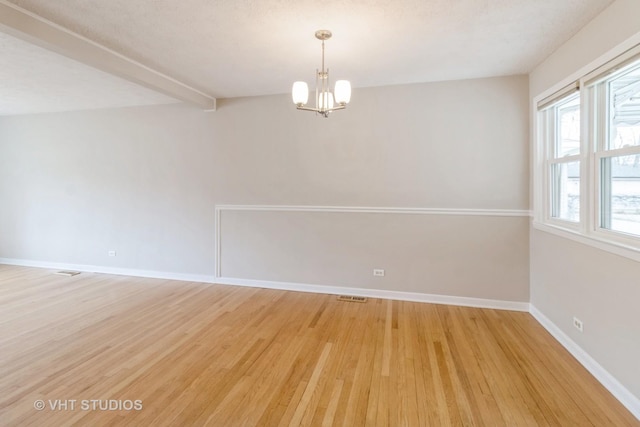 spare room with hardwood / wood-style flooring, a chandelier, a textured ceiling, and beamed ceiling