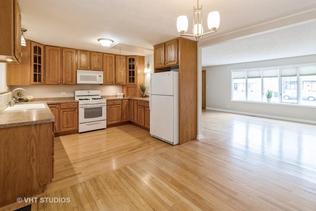 kitchen with sink, hanging light fixtures, white appliances, light hardwood / wood-style floors, and an inviting chandelier