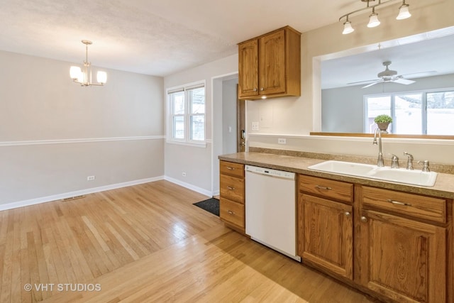 kitchen with decorative light fixtures, sink, white dishwasher, plenty of natural light, and light hardwood / wood-style flooring