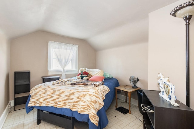 bedroom with lofted ceiling and baseboards