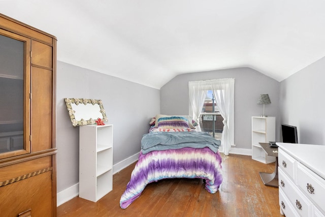 bedroom with vaulted ceiling, wood finished floors, and baseboards