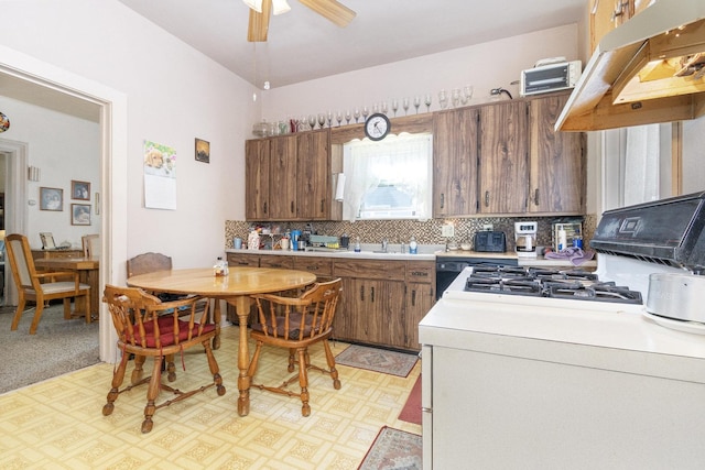 kitchen with ceiling fan, light countertops, under cabinet range hood, brown cabinets, and backsplash