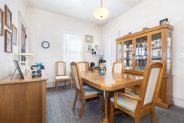 dining space with plenty of natural light, baseboards, dark colored carpet, and ornamental molding